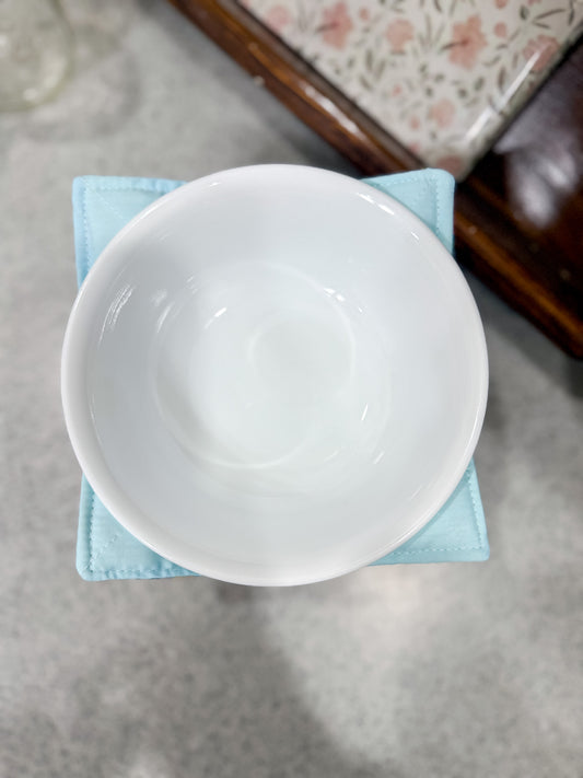 White ceramic bowl on a light blue napkin with a floral-patterned surface in the background