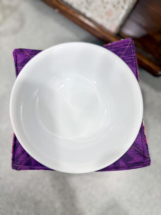 White ceramic bowl on a purple fabric with a blurred background