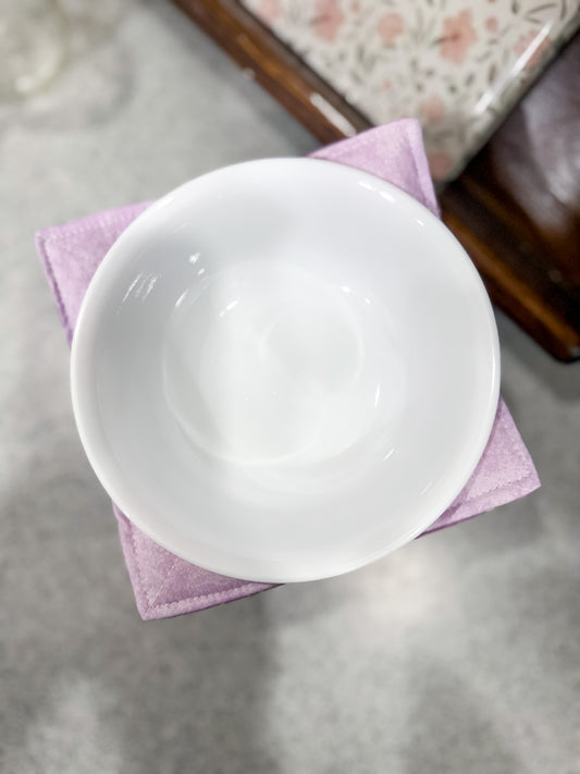 White ceramic bowl on a pink cloth with a blurred background