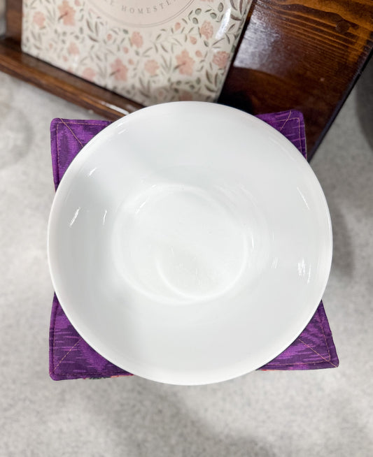White bowl on a purple napkin with a floral patterned box in the background