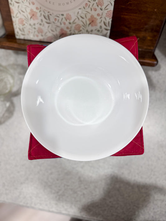 White ceramic bowl on a red cloth with a floral-patterned box in the background