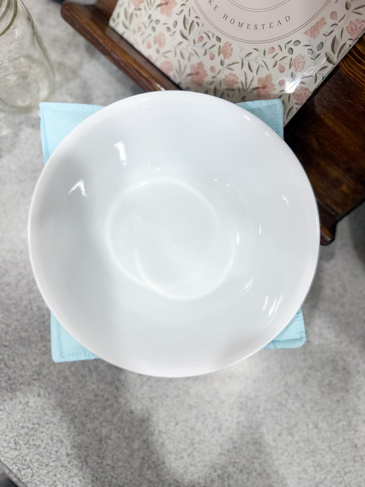 White ceramic bowl on a gray surface with a floral-patterned box in the background.