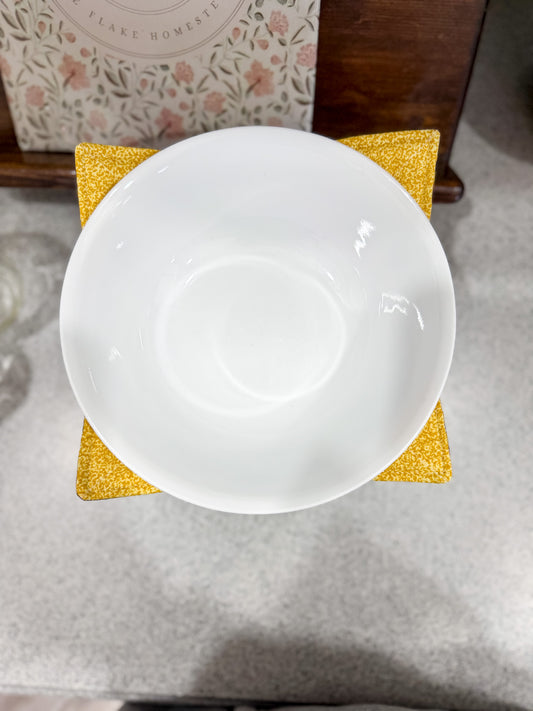 White ceramic plate on a yellow coaster with a floral-patterned napkin in the background.