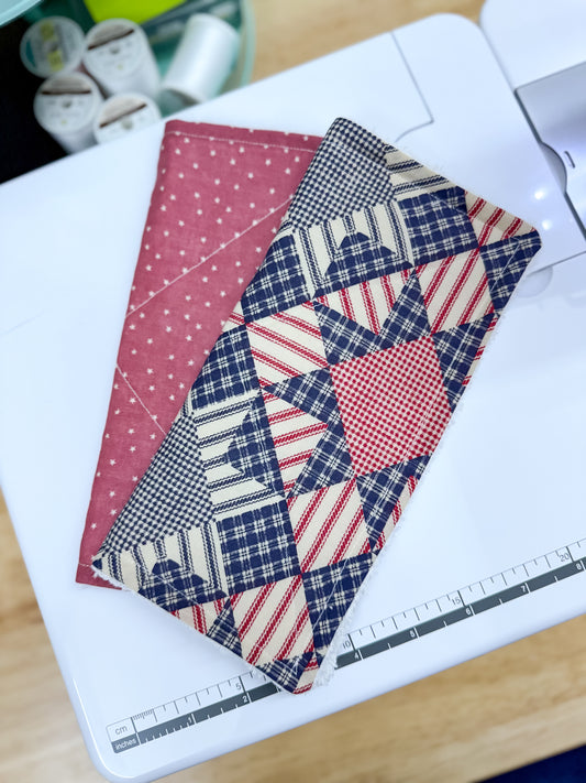 Quilted fabric samples on a cutting mat with a sewing machine in the background