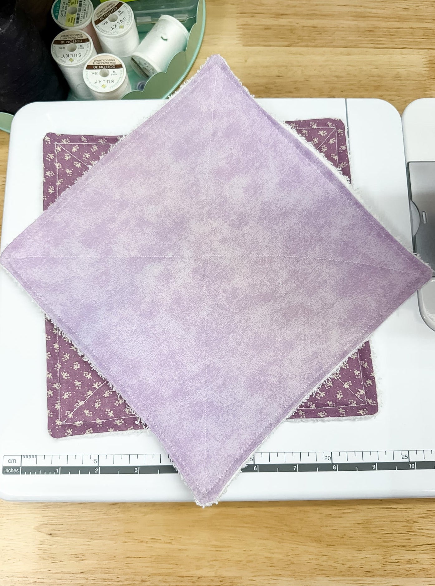Purple fabric on a cutting mat with a ruler, on a wooden surface.