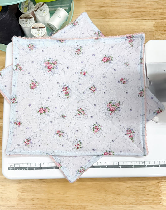 Floral fabric on a sewing machine with sewing supplies in the background