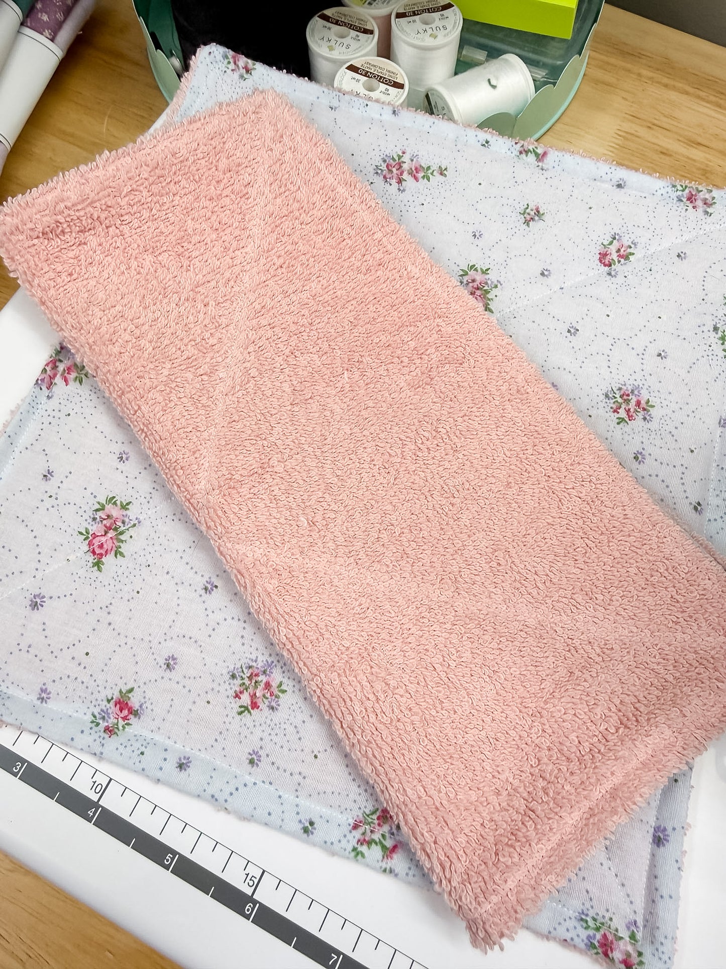 Pink fabric on a floral-patterned surface with a ruler for scale.