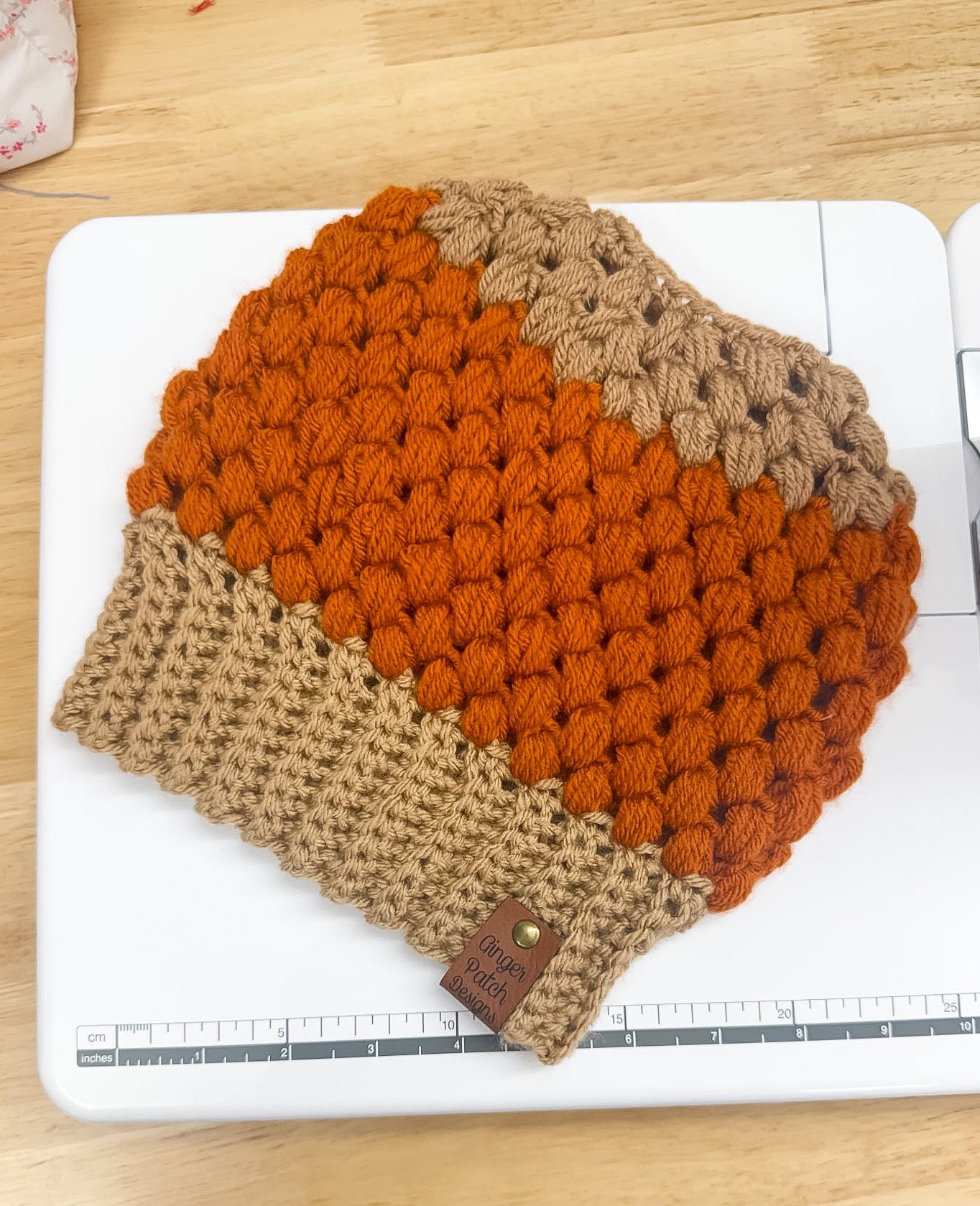 Crocheted beanie with orange and brown gradient on a white surface