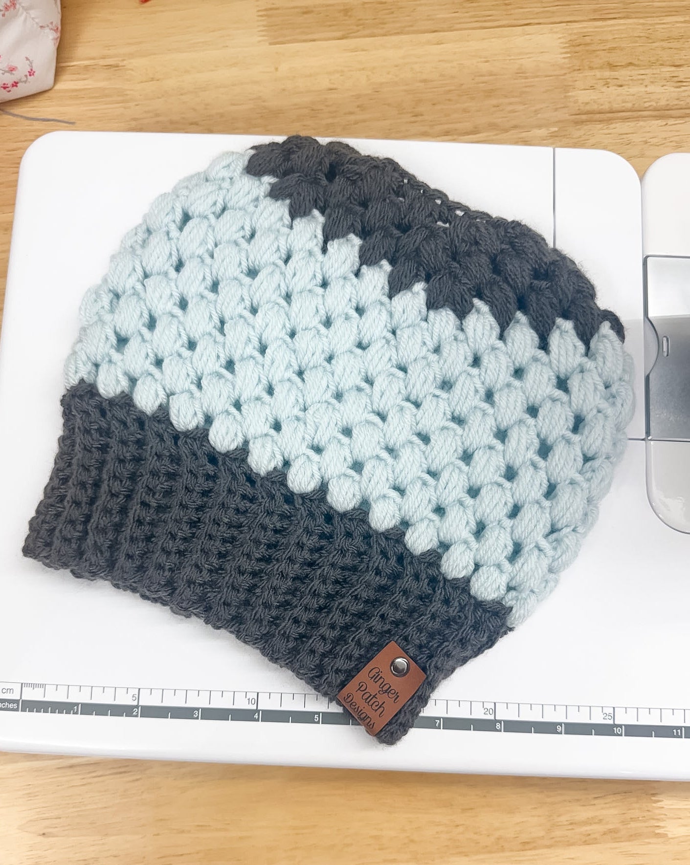 Knitted beanie with gray and light blue pattern on a wooden surface