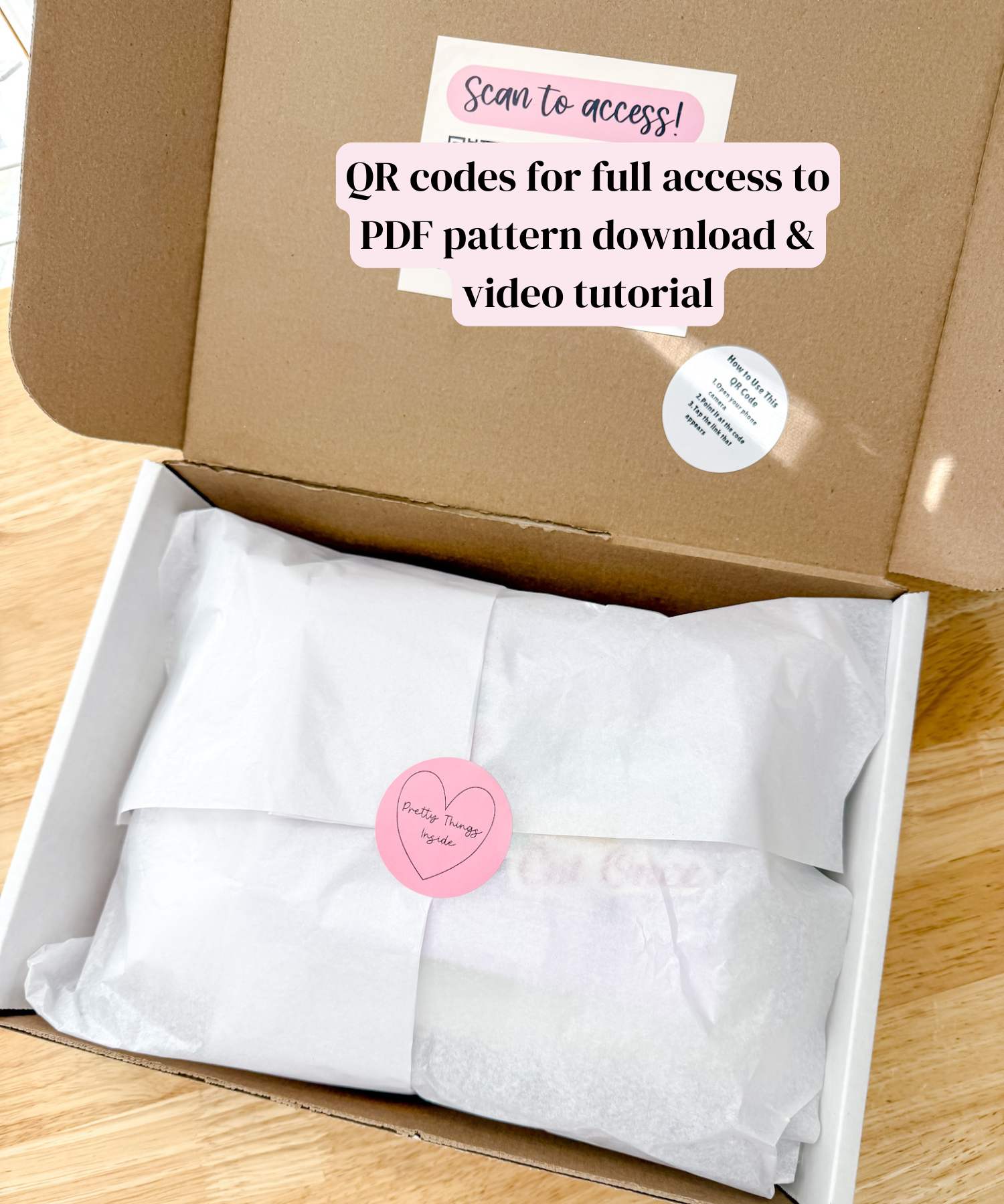 Open box with white fabric and QR code labels on a wooden surface