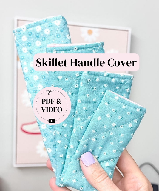 A hand holds three quilted fabric handle covers in a light aqua blue color with a small white floral pattern. The image features text overlays reading 'Skillet Handle Cover' and 'PDF & VIDEO'.