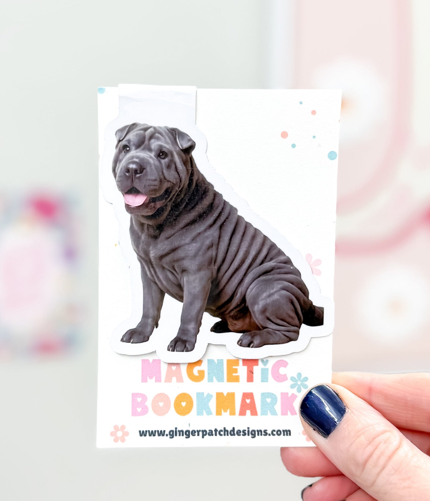 Magnetic bookmark with a dog design held by a hand against a colorful background