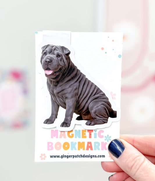 Magnetic bookmark with a dog design held by a hand against a colorful background