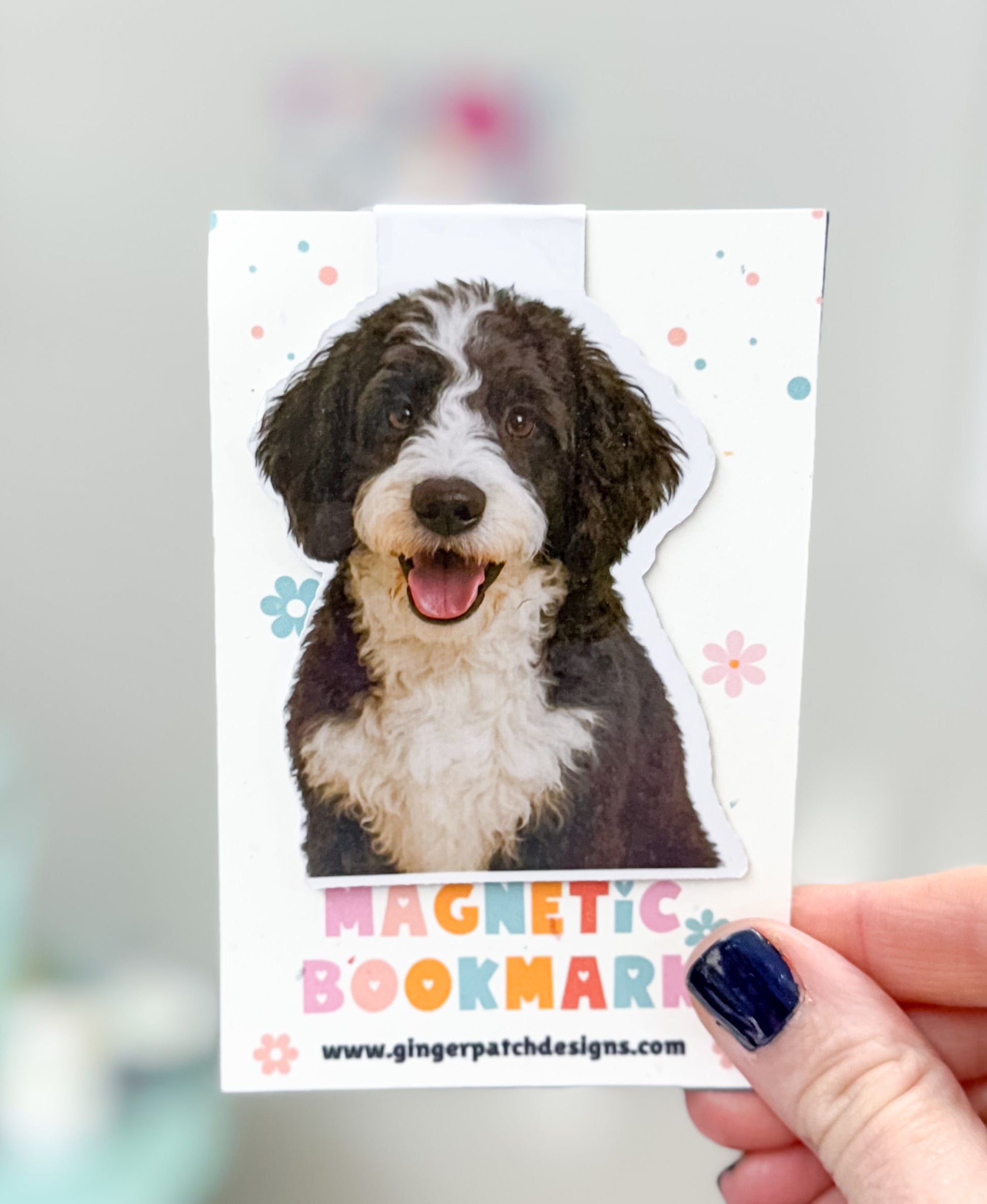 Magnetic bookmark with a dog illustration held by a hand against a blurred background
