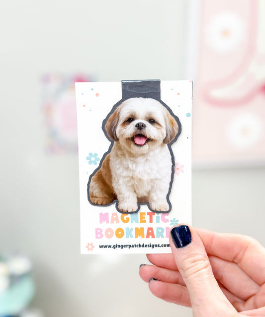 Magnetic bookmark with a dog illustration held by a hand against a blurred background
