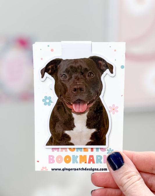 Dog-shaped bookmark held by a hand with a blurred background