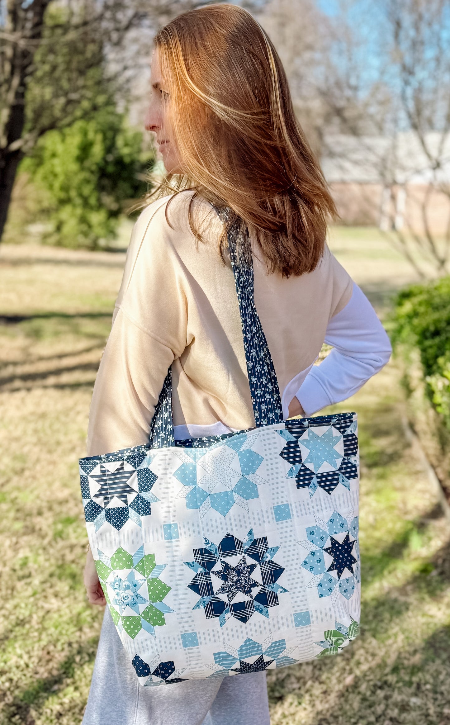 Woman holding a patterned tote bag outdoors