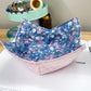 Floral-patterned fabric folded into a boat shape on a table with a ruler in the foreground.
