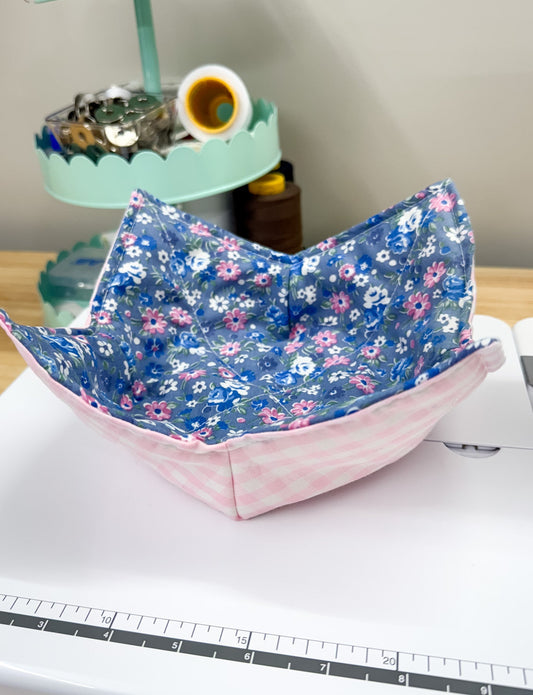Floral-patterned fabric folded into a boat shape on a table with a ruler in the foreground.