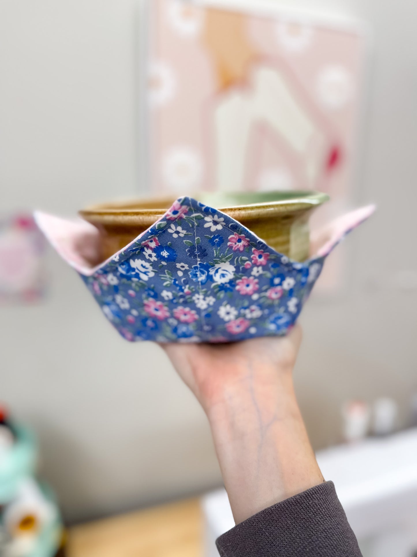 Hand holding a small floral-patterned bowl with a blurred background
