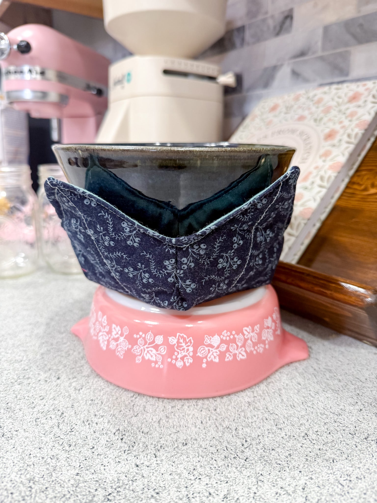 Pink ceramic dish with a blue floral patterned lid on a kitchen counter.