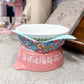 Decorative bowl with floral pattern on a pink base on a kitchen counter.