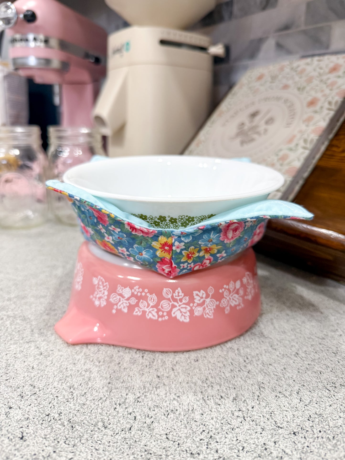Decorative bowl with floral pattern on a pink base on a kitchen counter.