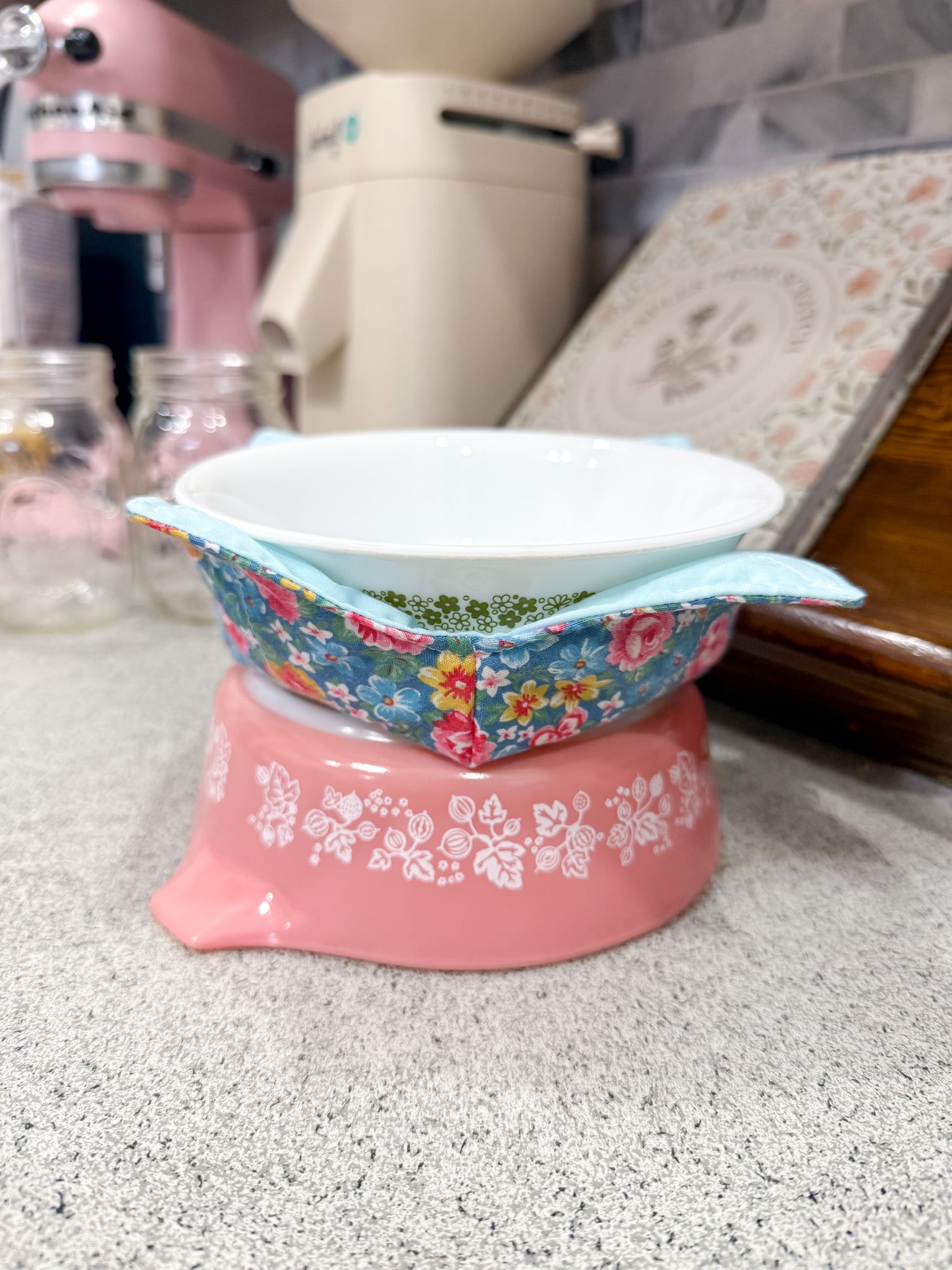 Decorative bowl with floral pattern on a pink base on a kitchen counter.