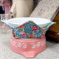 Pink footstool with floral-patterned cover on a speckled surface