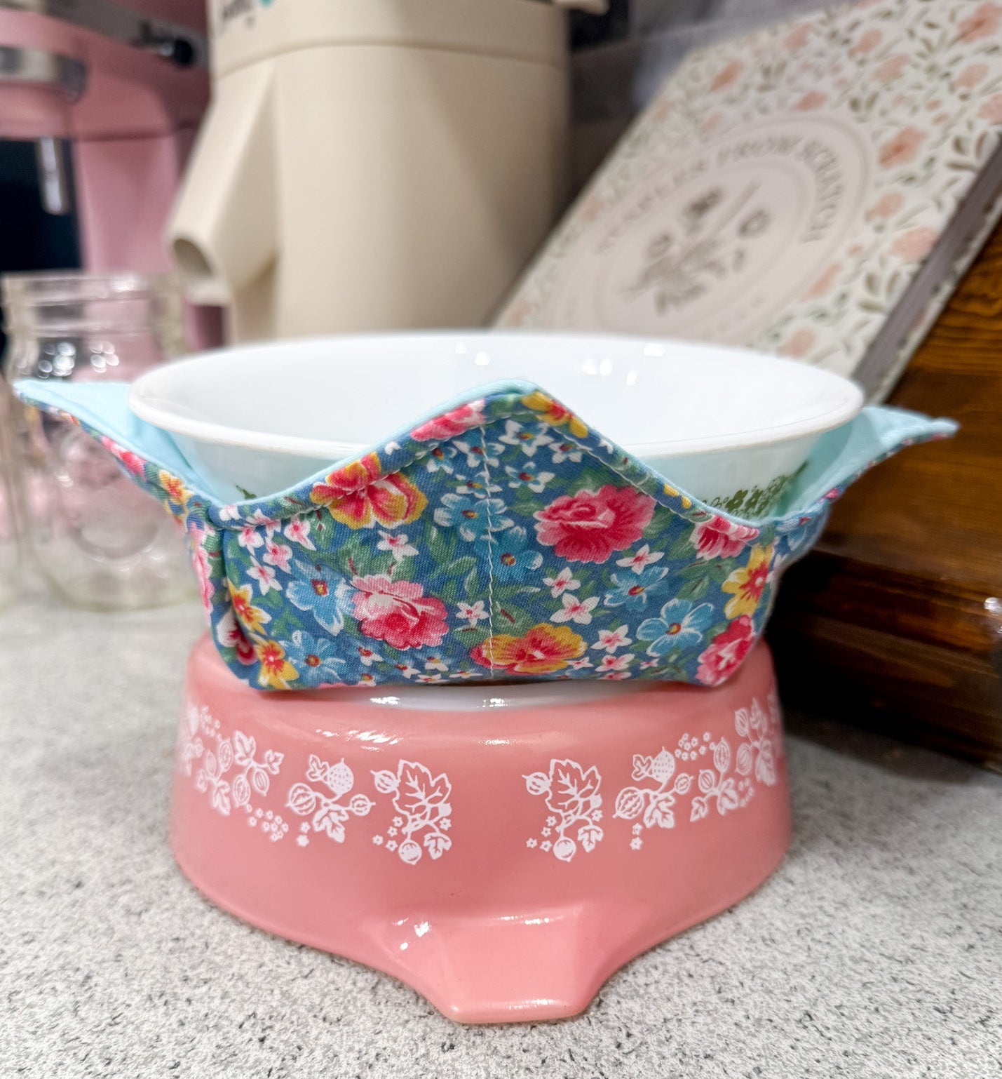 Pink footstool with floral-patterned cover on a speckled surface
