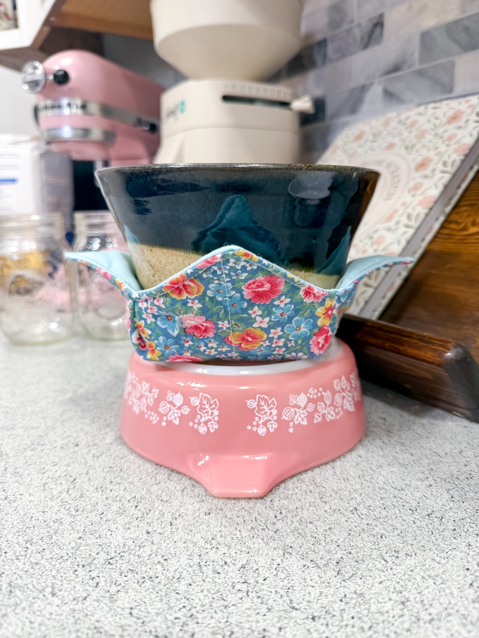Ceramic bowl in floral pattern fabric bowl cozy on a pink base in a kitchen setting
