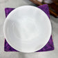 White ceramic bowl on a purple fabric with a blurred background