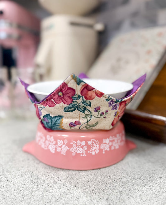 Pink pet bowl with floral patterned cover on a textured surface