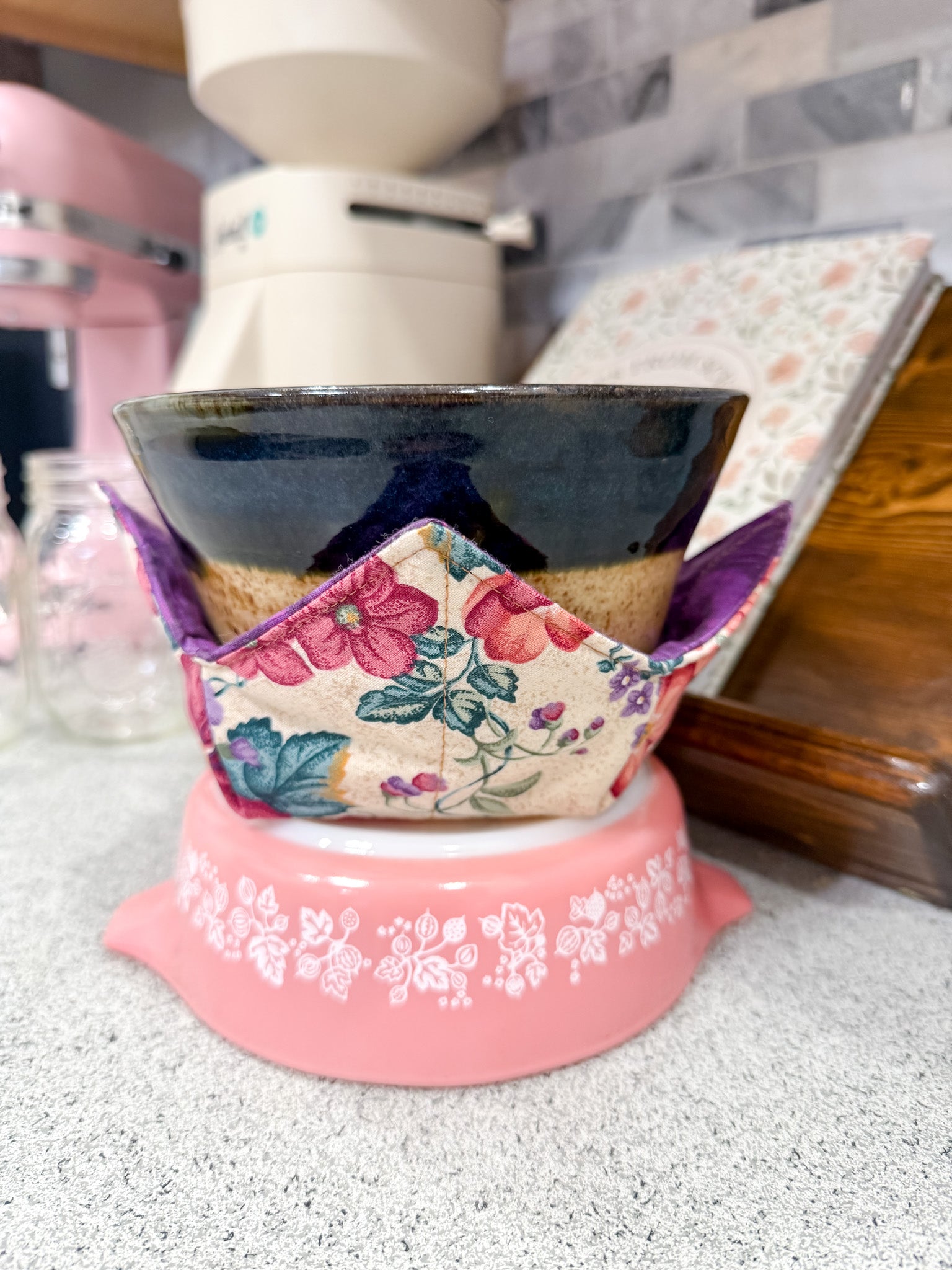 Decorative pink stand with a floral fabric cover holding a black bowl.