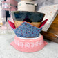 Ceramic pot with a blue floral cover on a pink stand in a kitchen setting