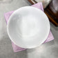 White ceramic bowl on a pink cloth with a blurred background