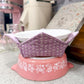 Pink and white decorative bowl with a purple lid on a kitchen counter.