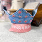 Pink stand with a blue floral pot holder on a kitchen counter