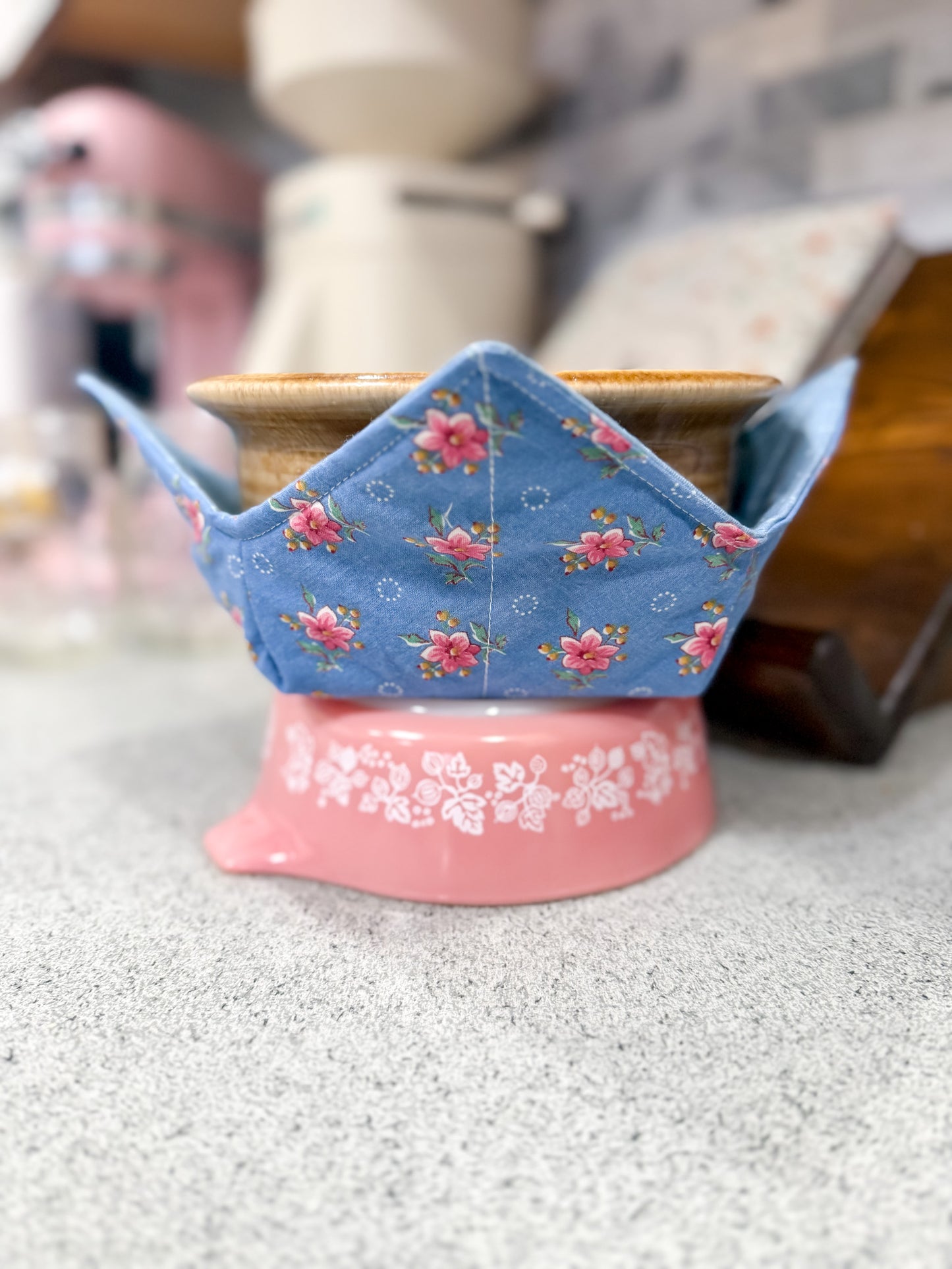Pink stand with a blue floral pot holder on a kitchen counter