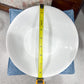 White bowl with a measuring tape on top, held by a hand, against a neutral background.