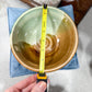 Ceramic bowl with a measuring tape for scale on a textured surface