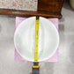 Person measuring a white plate with a tape measure on a gray surface.