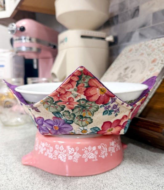 Floral-patterned container on a pink base with kitchen appliances in the background