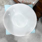 White ceramic bowl on a gray surface with a floral-patterned box in the background.