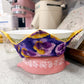 Pink kitchen scale with floral-patterned lid on a speckled countertop