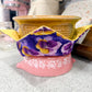 Decorative pot with floral design on a pink base, placed on a countertop.