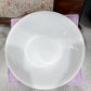 White ceramic bowl on a purple napkin with a floral-patterned dishcloth in the background.