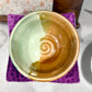 Ceramic bowl with a spiral design on a purple coaster