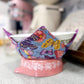 Colorful butterfly-patterned fabric on a white bowl with a pink base.