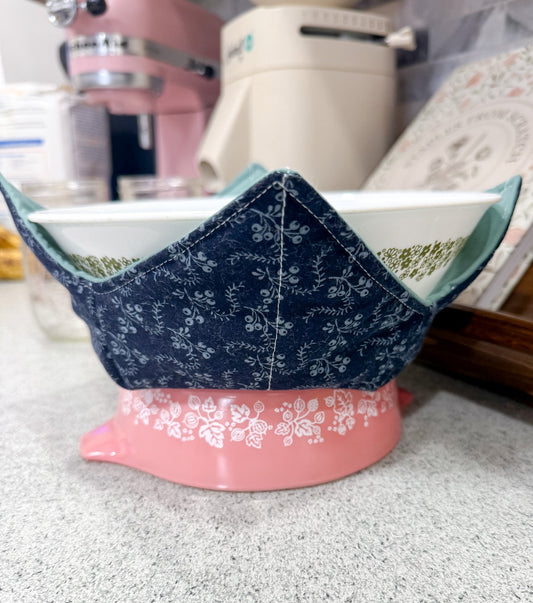 Blue floral-patterned bowl on a pink stand with kitchen items in the background